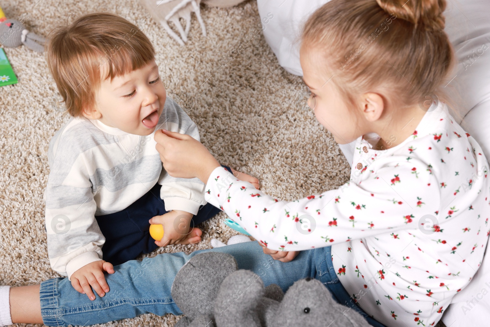 Photo of Sister and brother spending time together on floor at home