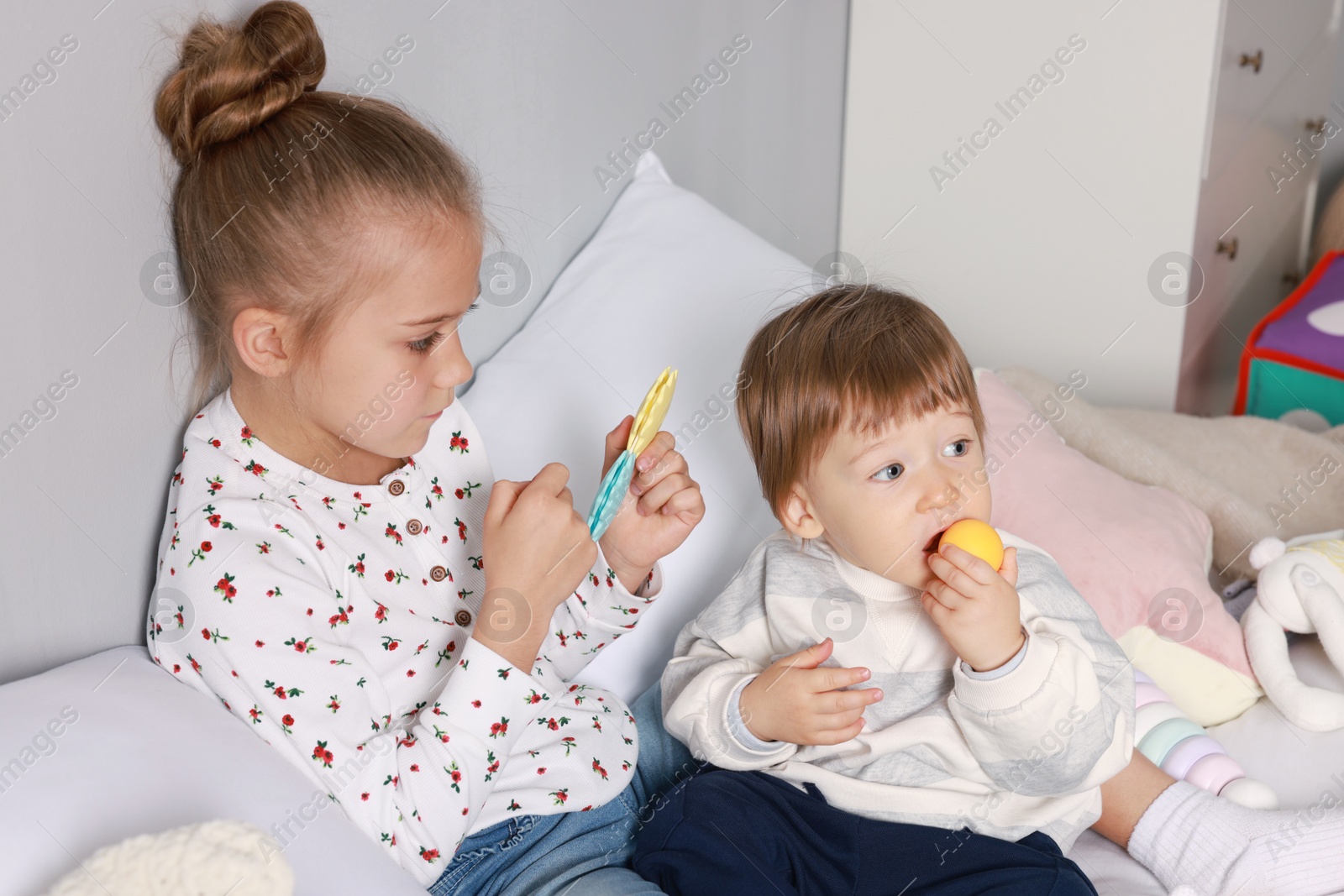 Photo of Sister and brother playing together on bed indoors