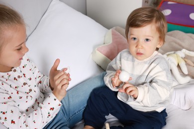 Photo of Sister and brother playing together on bed indoors