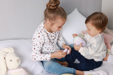 Photo of Sister and brother playing with toy pyramid on bed indoors