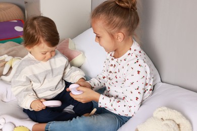 Photo of Sister and brother playing with toy pyramid on bed indoors