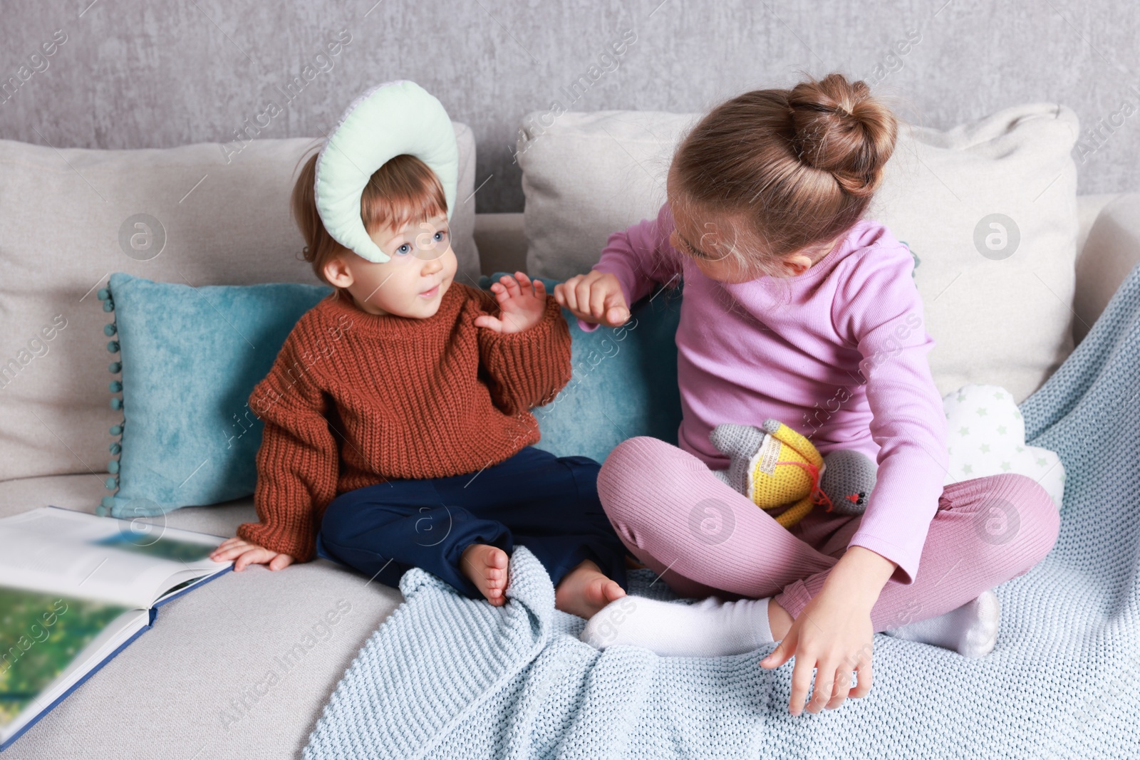 Photo of Sister and brother playing together on bed indoors