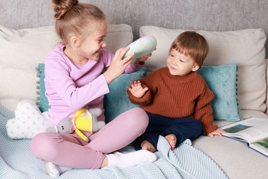 Photo of Sister and brother playing together on bed indoors