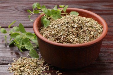 Photo of Dried oregano in bowl and green leaves on wooden table, closeup