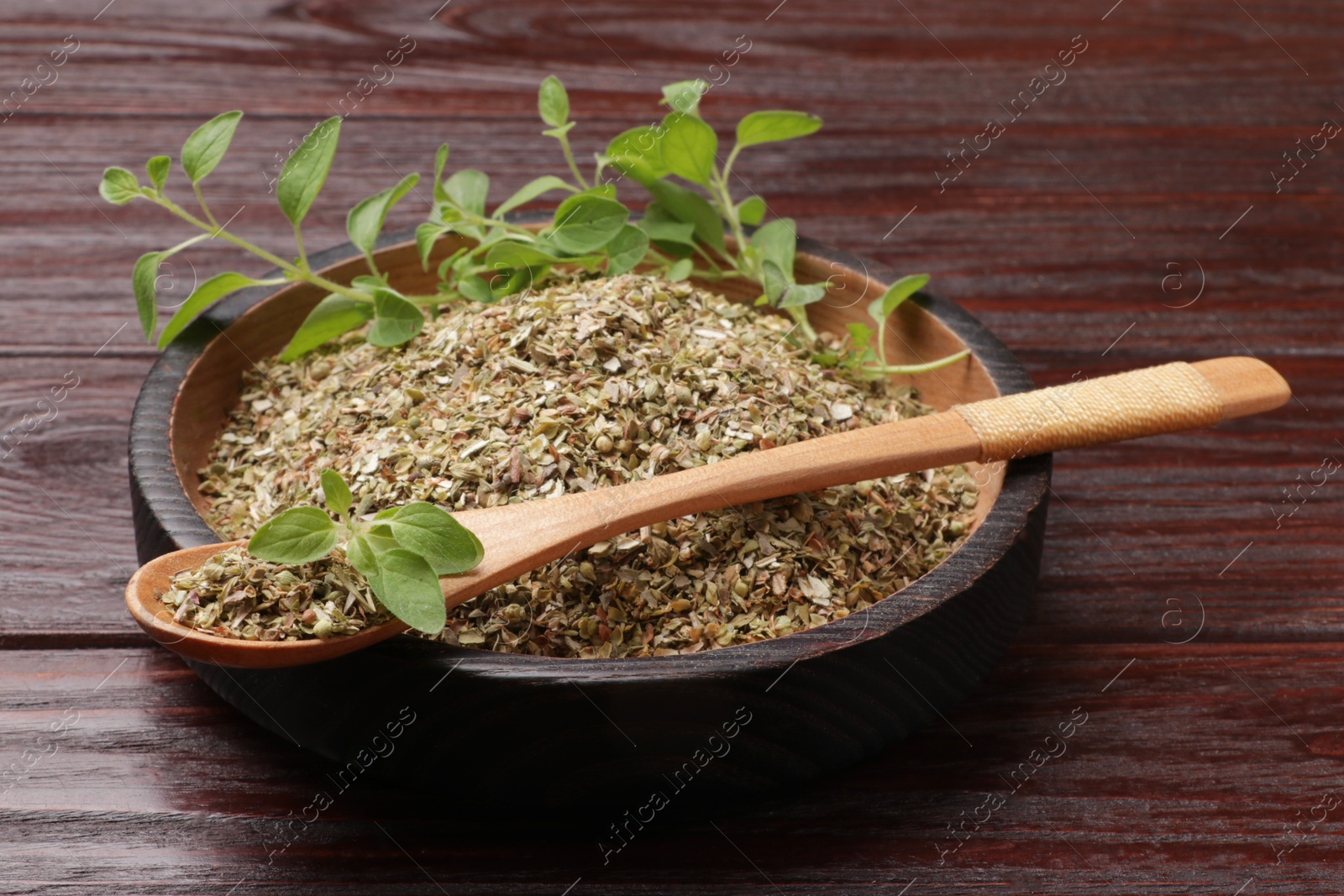 Photo of Dried oregano and green leaves on wooden table, closeup