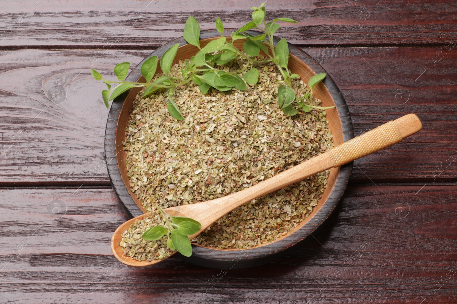 Photo of Dried oregano and green leaves on wooden table, top view