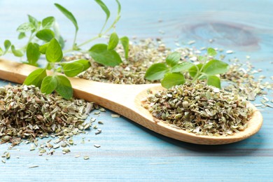 Dried oregano in spoon and green leaves on light blue wooden table, closeup