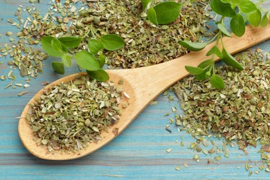 Photo of Dried oregano in spoon and green leaves on light blue wooden table, closeup