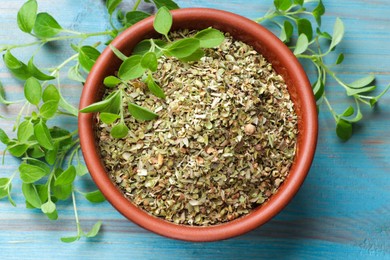 Photo of Dried oregano in bowl and green leaves on light blue wooden table, top view