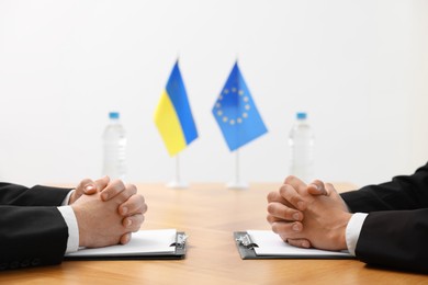 Photo of Diplomats negotiating during meeting at wooden table indoors, closeup