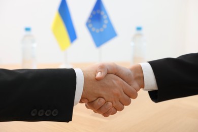 Photo of Diplomats shaking hands during meeting indoors, closeup