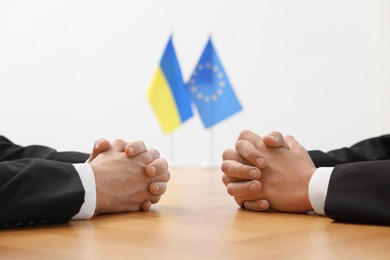 Diplomats negotiating during meeting at wooden table indoors, closeup