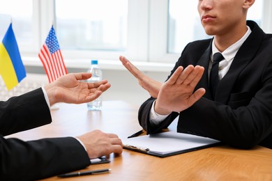 Diplomats negotiating during meeting at wooden table indoors, closeup