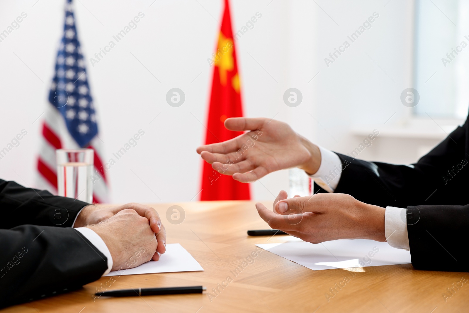 Photo of Diplomats negotiating during meeting at wooden table indoors, closeup