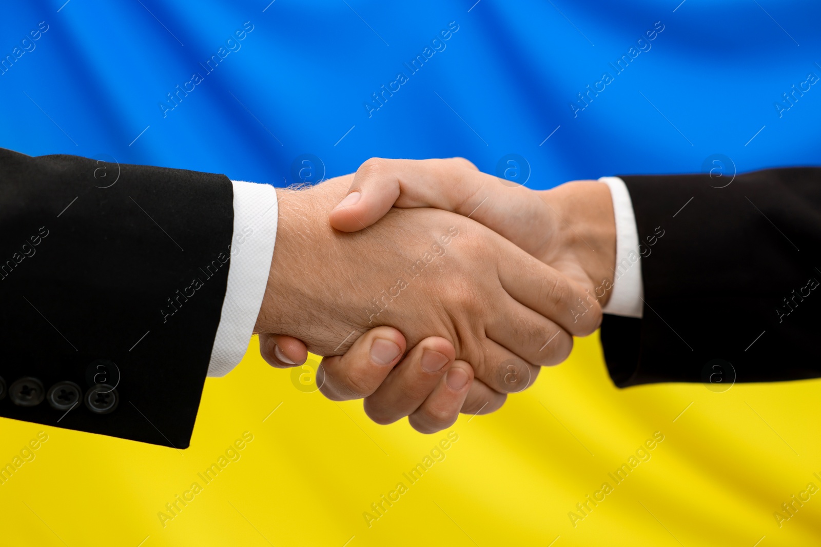 Photo of Diplomats shaking hands against flag of Ukraine, closeup