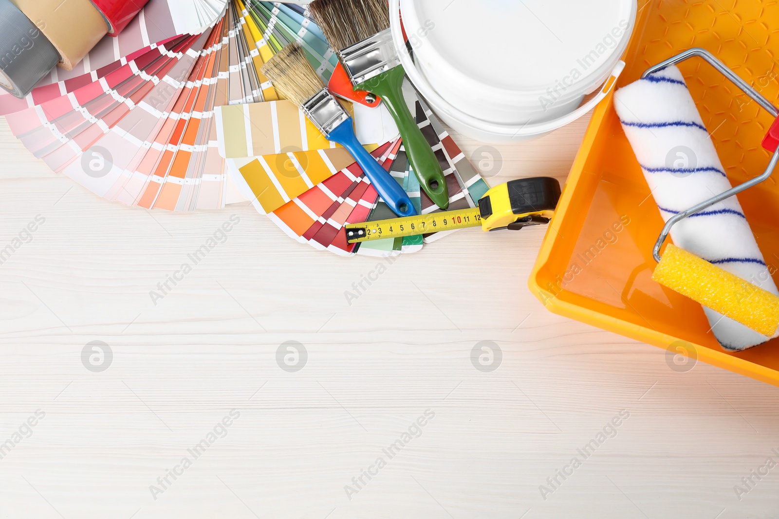 Photo of Decorating and design. Different painter's tools on white wooden table, flat lay. Space for text