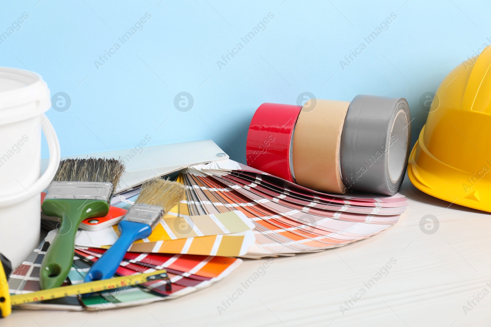 Photo of Different painter's tools on white wooden table. Decorating and design