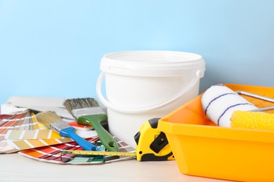 Photo of Different painter's tools on white wooden table. Decorating and design