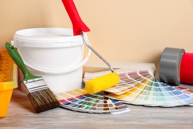 Photo of Different painter's tools on light wooden table. Decorating and design