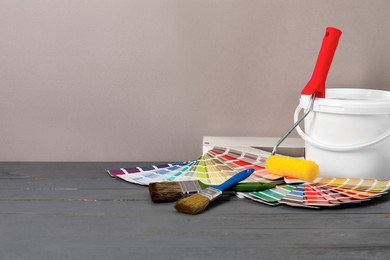 Photo of Different painter's tools on grey wooden table, space for text. Decorating and design