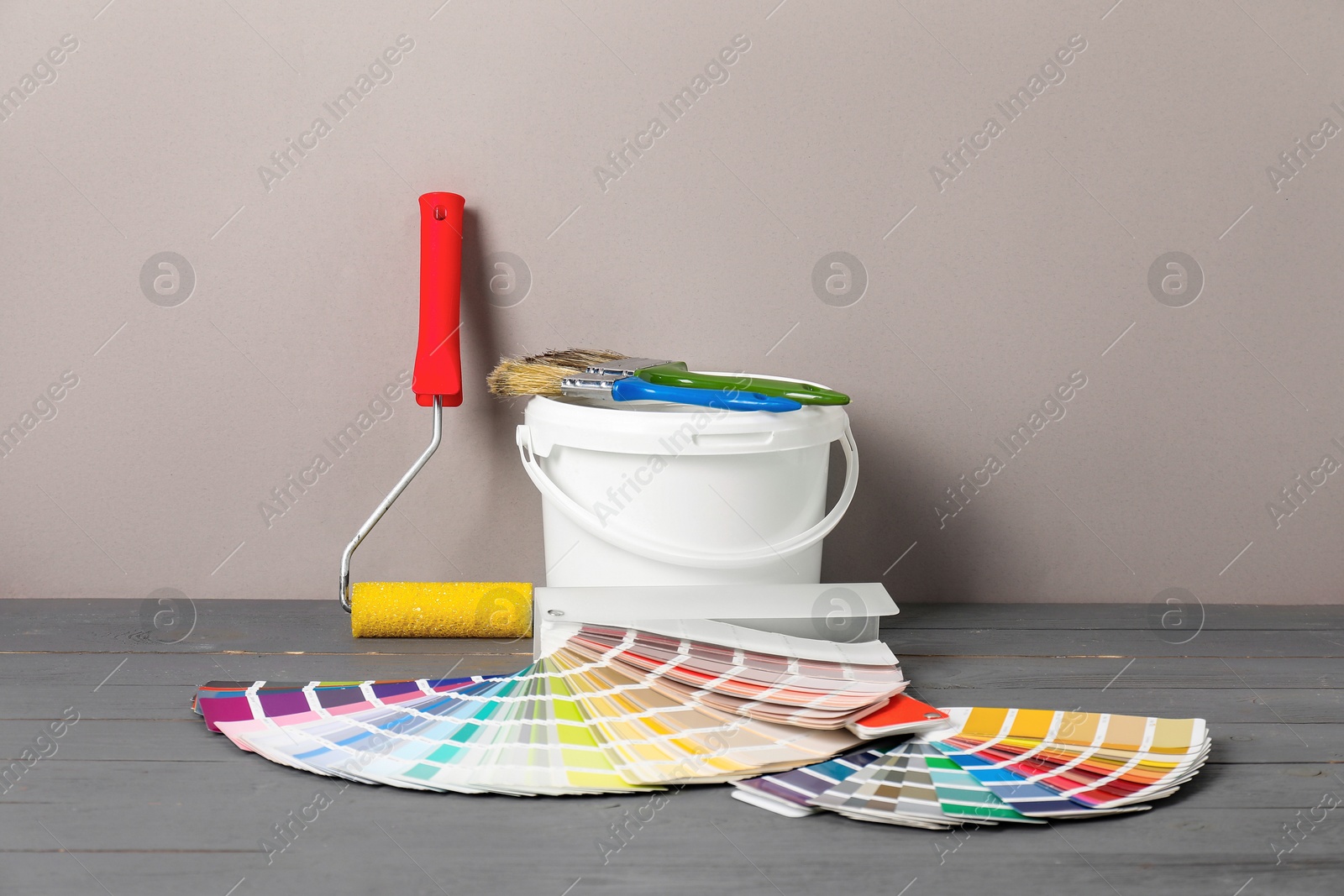 Photo of Different painter's tools on grey wooden table. Decorating and design