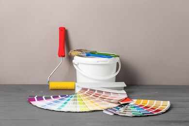 Photo of Different painter's tools on grey wooden table. Decorating and design