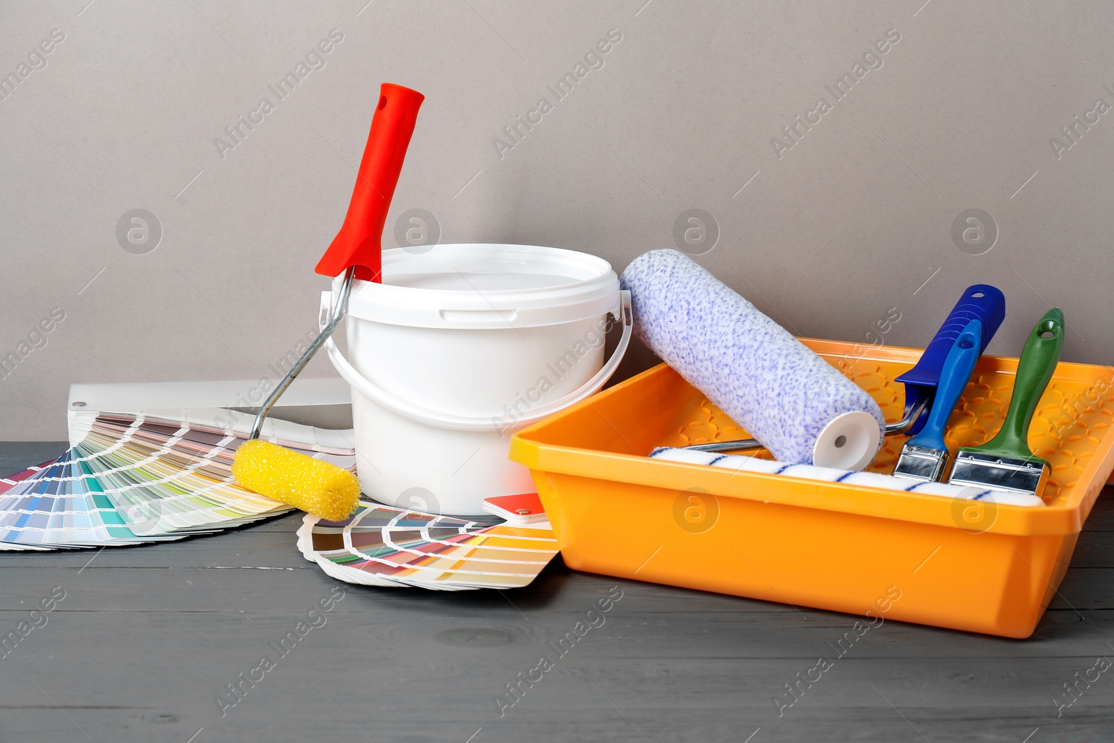 Photo of Different painter's tools on grey wooden table. Decorating and design