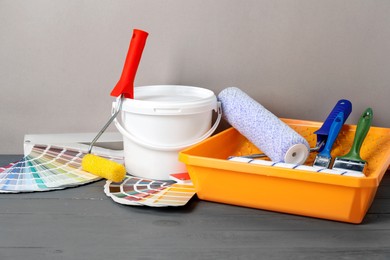 Photo of Different painter's tools on grey wooden table. Decorating and design