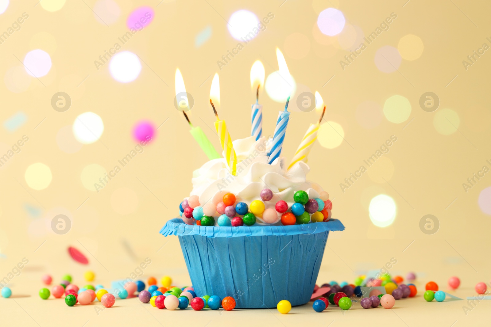 Photo of Tasty cupcake with burning candles on beige background