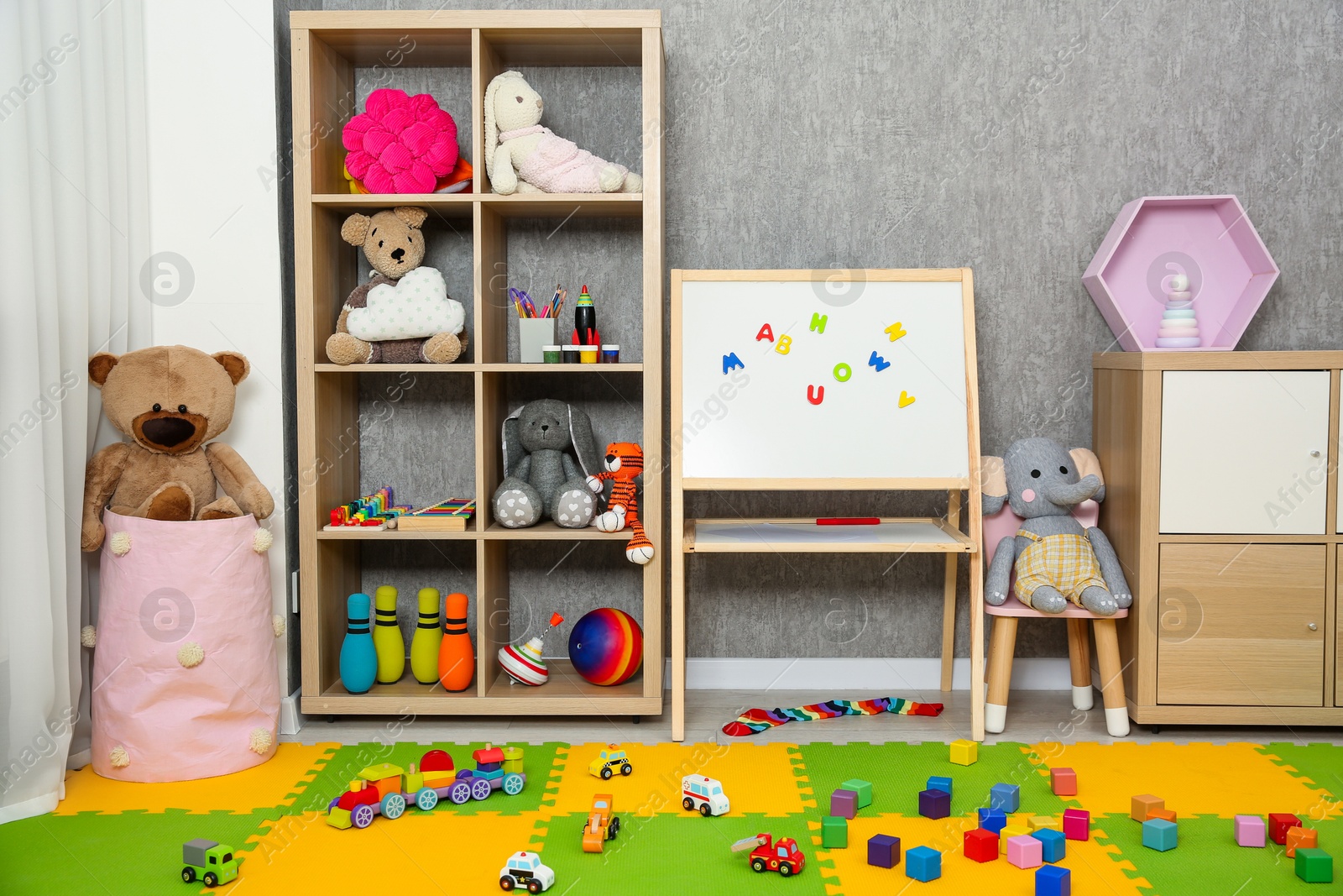 Photo of Beautiful kid's room interior with toys, whiteboard and stylish furniture