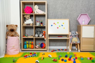 Photo of Beautiful kid's room interior with toys, whiteboard and stylish furniture