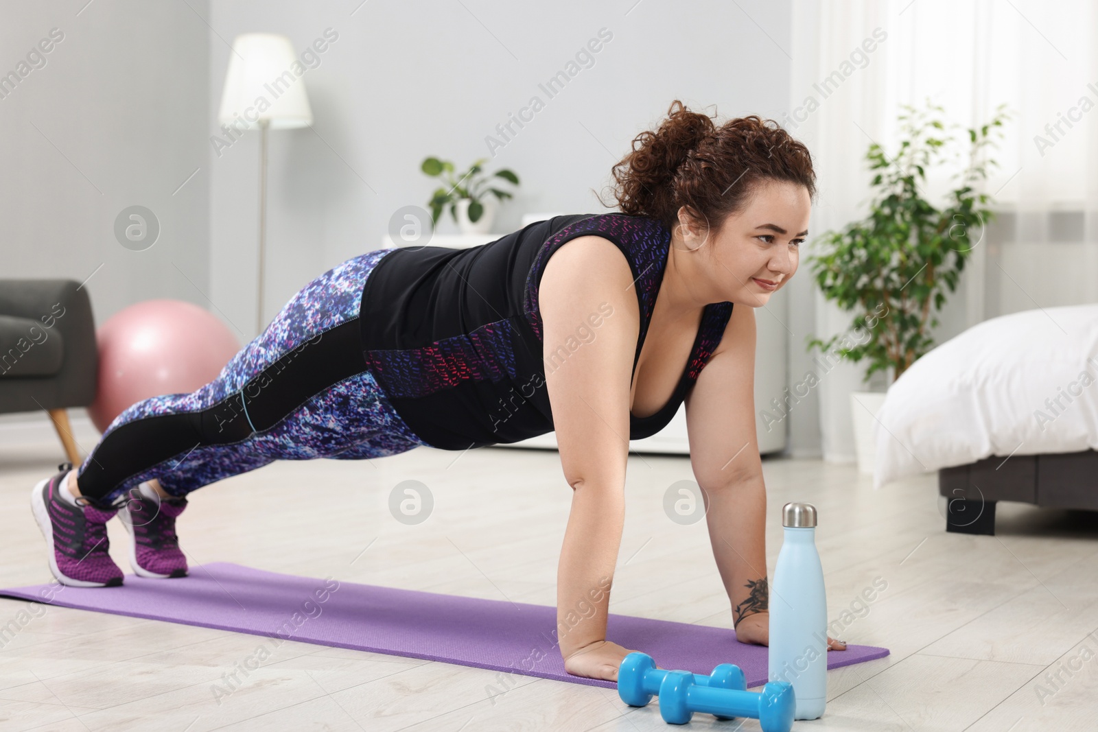 Photo of Woman doing plank exercise on fitness mat at home