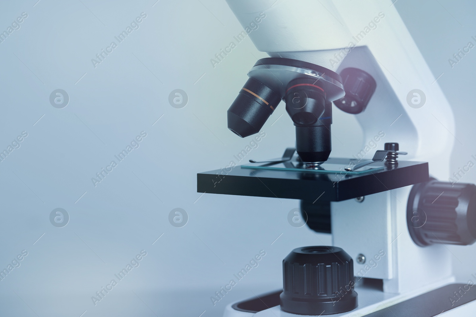 Photo of Science. Microscope with glass slide on light grey background, closeup. Space for text