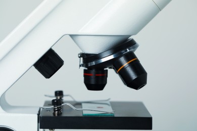 Photo of Science. Microscope with glass slide on light grey background, closeup