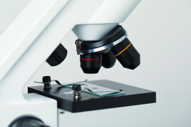 Photo of Science. Microscope with glass slide on light grey background, closeup