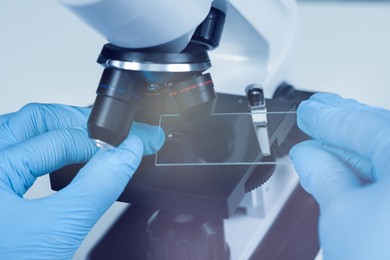 Photo of Scientist working with microscope in laboratory, closeup