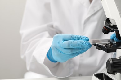 Photo of Scientist working with microscope in laboratory, closeup