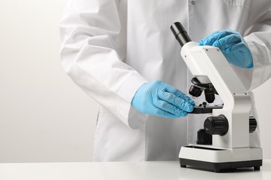 Photo of Scientist working with microscope in laboratory, closeup