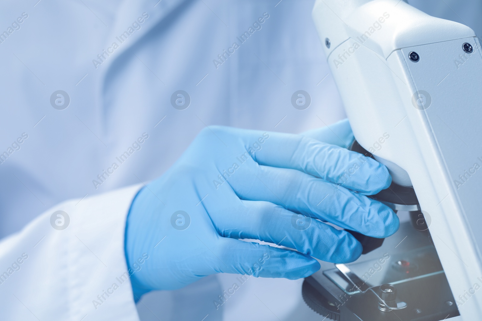 Photo of Scientist examining sample on slide under microscope, closeup