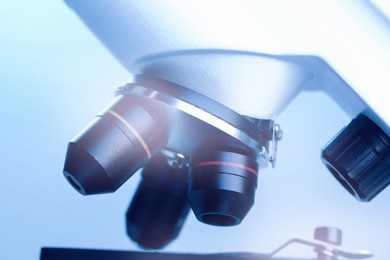 Photo of Science. Modern microscope on light blue background, closeup