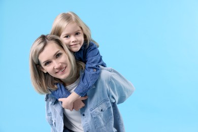 Photo of Cute little girl hugging her mom on light blue background, space for text. Happy Mother's Day