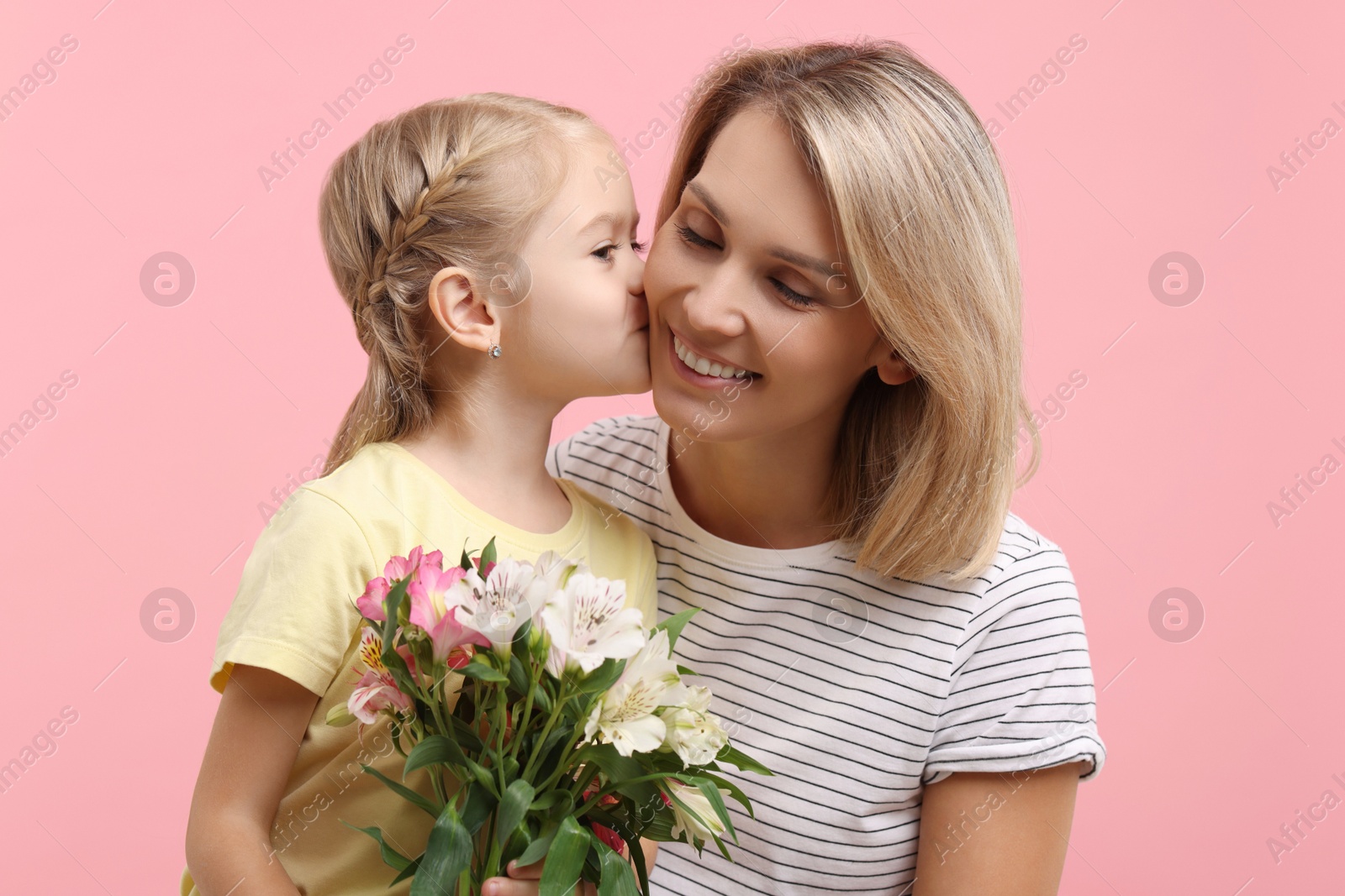 Photo of Little daughter congratulating her mom with bouquet of alstroemeria flowers on pink background. Happy Mother's Day