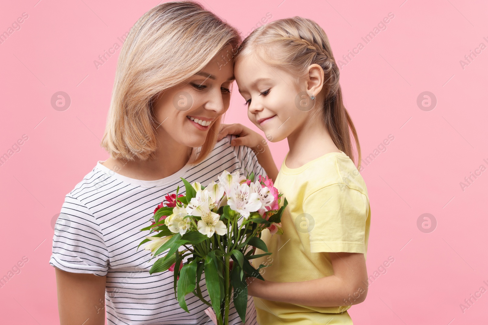 Photo of Little daughter congratulating her mom with bouquet of alstroemeria flowers on pink background. Happy Mother's Day