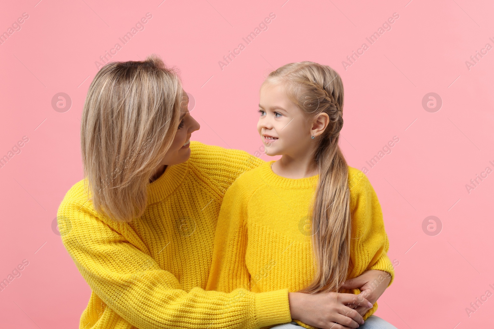 Photo of Cute little girl with her mom on pink background. Happy Mother's Day