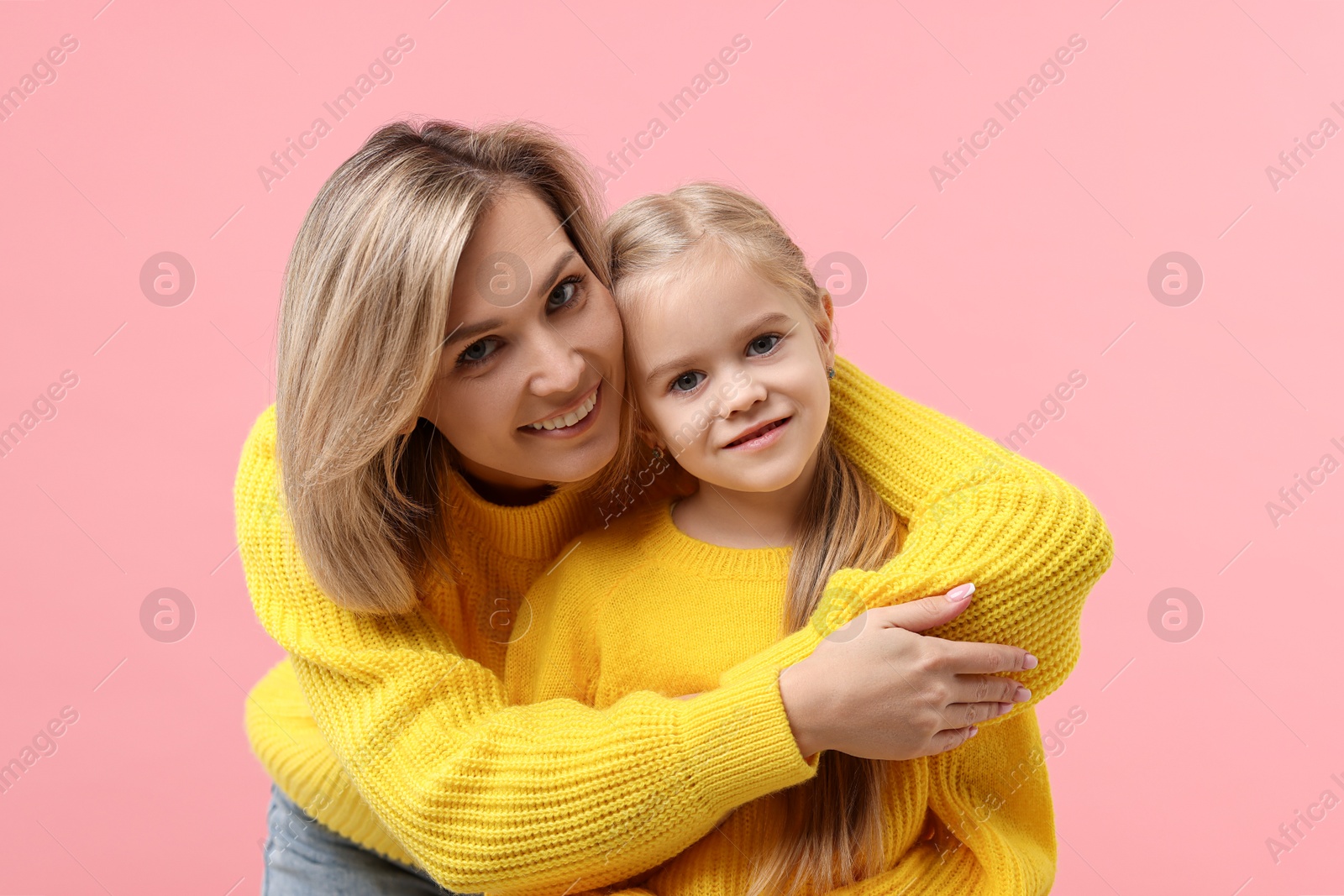 Photo of Cute little girl with her mom on pink background. Happy Mother's Day