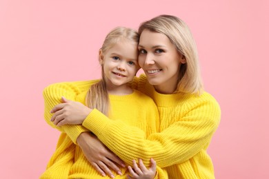 Photo of Cute little girl with her mom on pink background. Happy Mother's Day