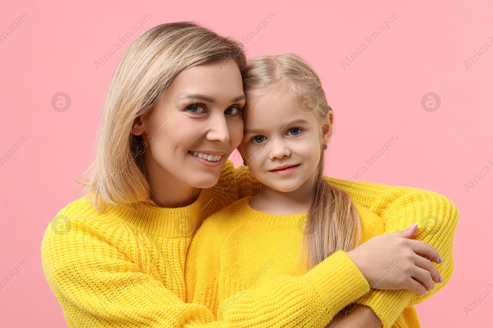 Photo of Cute little girl with her mom on pink background. Happy Mother's Day