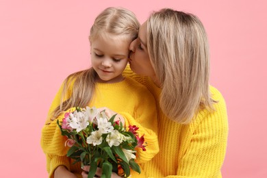 Photo of Woman with her daughter and bouquet of alstroemeria flowers on pink background. Mother's Day celebration