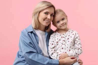 Photo of Cute little girl with her mom on pink background. Happy Mother's Day