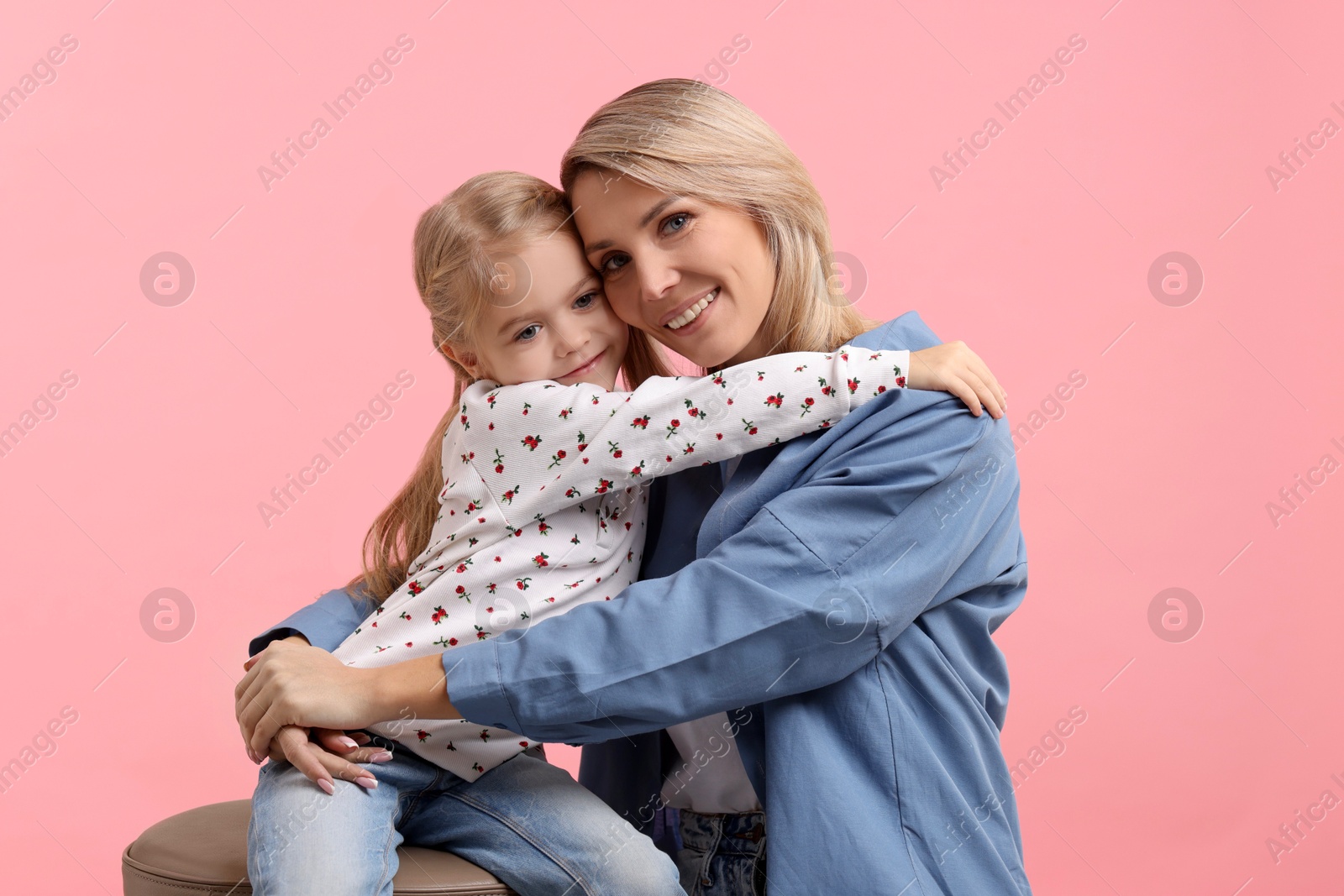 Photo of Cute little girl hugging her mom on pink background. Happy Mother's Day